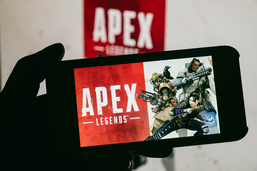 a person holding up a cell phone with a picture of apexx on the screen