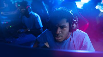 A gamer playing in a Valorant tournament next to other players