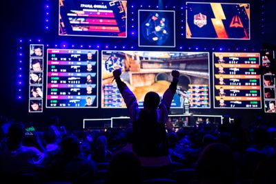 Gamer fan standing up and cheering in front of scoreboard at League of Legends event