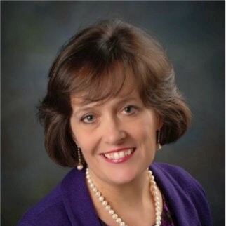 a woman wearing a purple jacket and pearls