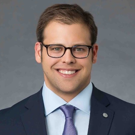 a man in a suit and tie smiling at the camera