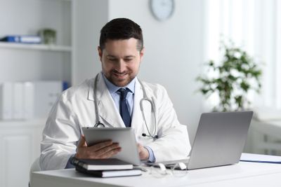 A doctor looking up information and knowledge management on a tablet.