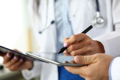 a doctor holding a tablet and writing on it