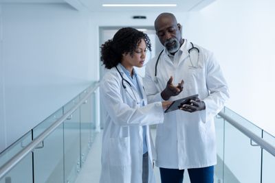 a man and a woman in white lab coats looking at something on a tablet