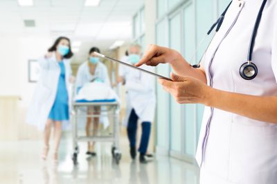 a nurse holding a tablet in a hospital hallway