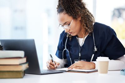 a woman with a stethoscope writing on a notebook