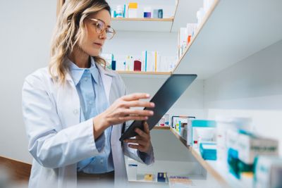 a woman in a lab coat looking at a tablet