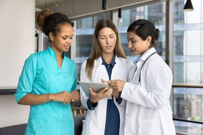 a group of healthcare workers including nurse looking at something on a tablet