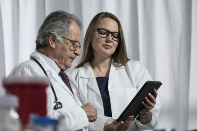a doctor and a patient looking at clinical guidance on a tablet