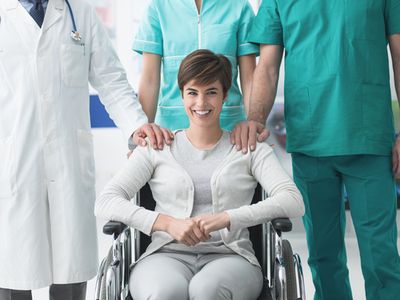 a woman in a wheelchair with a group of doctors behind her