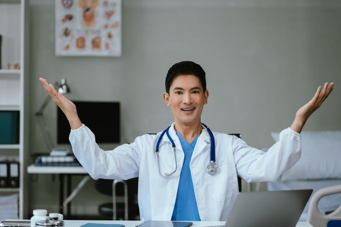 A male doctor sitting in an office with open arms.