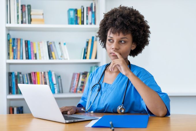 A female doctor sitting at a table with a laptop.