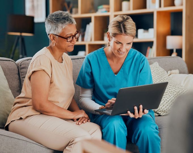 A female doctor presenting something on a laptop to a patient.