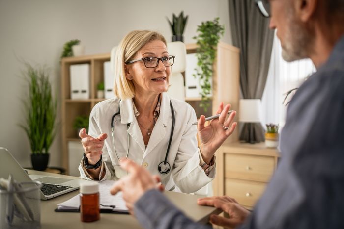 A doctor talking to a patient about his satisfaction to improve care.