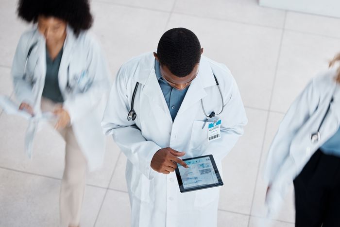 a man in a white lab coat holding a tablet