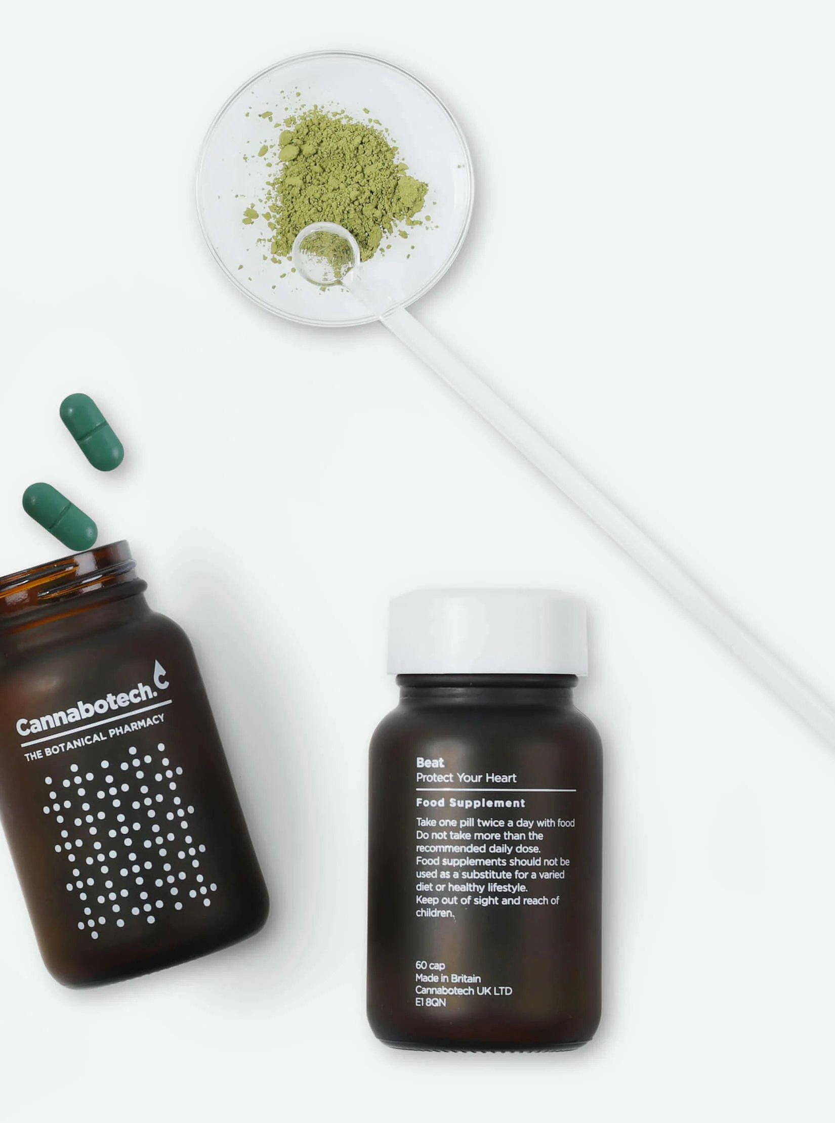 A spoon and a jar of green CBD powder next to two jars of Cannabotech's Beat Food Supplements