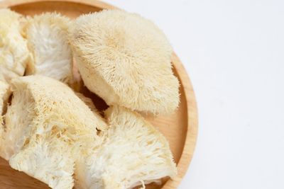 Pieces of fresh lion's mane mushroom placed on a wooden plate, on a table.