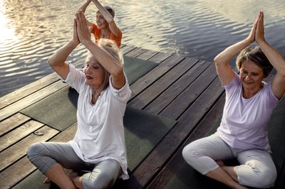 Elderly women doing yoga by the ocean to relieve sacroiliac joint pain