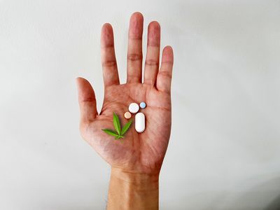 Open hand holding anti-inflammatory medications for rheumatoid arthritis and cannabis leaf