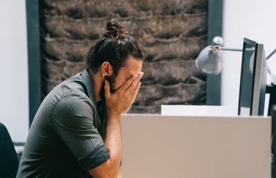 Stressed out entrepreneur holding his face in his hands