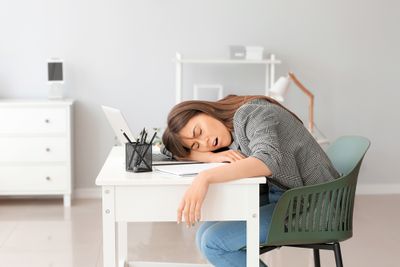 Woman sitting at office desk with head on the table and eyes closed