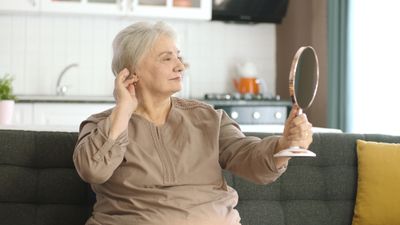 Older woman looking at herself in the mirror, visibly happy and in a pleasant mood