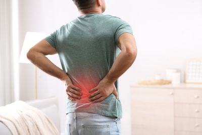 Man holding his hands on his lower back with red coloring indicating the area affected with chronic back pain that needs relief