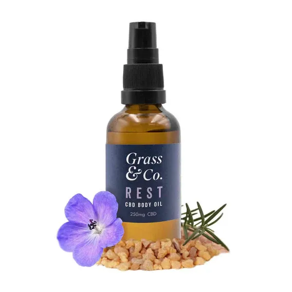 a bottle of grass and co rest with a flower