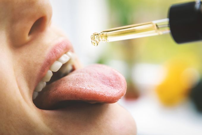 Woman placing CBD oil on her tongue out of a dropper