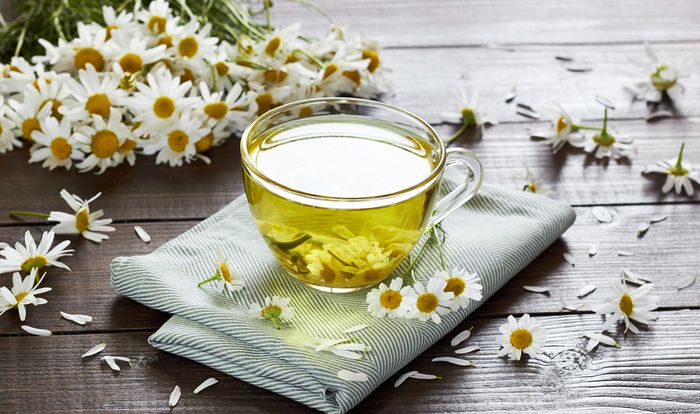 A clear cup of tea with Chamomile daisies in and around