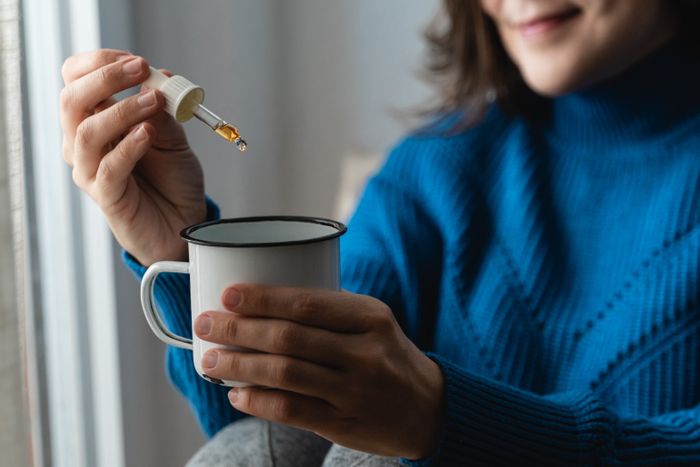 Woman adding CBD products to metal cup for anxiety problems