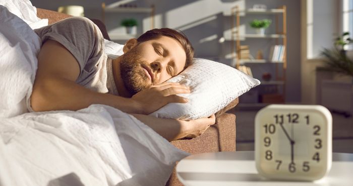 Man deep in sleep as his alarm is about to go off after getting a good night's rest