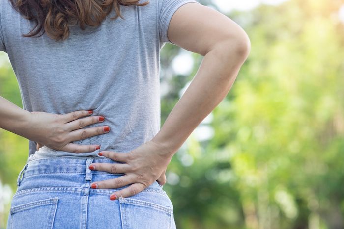 Woman clutching her lower back mid-walk due to chronic pain
