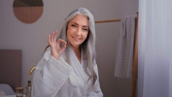 An image showing a happy older woman with grey hair and her hand in an okay motion