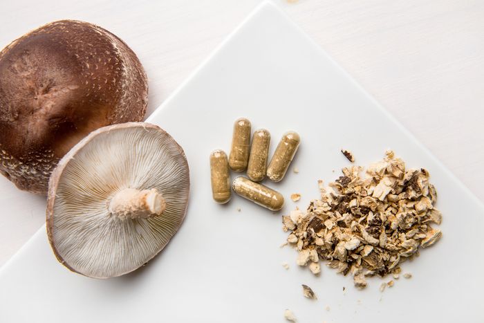 Fresh Shiitake mushrooms next to dried and ground Shiitake contained in supplement form