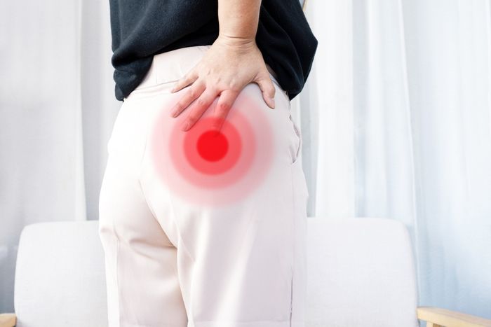 Woman standing pictured from behind with red marks on the picture indicating buttock muscle pain