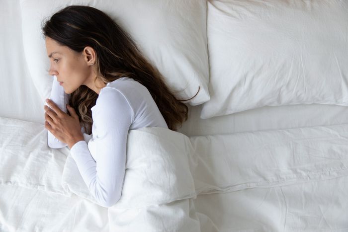 Woman coping with depression lying in bed during the day