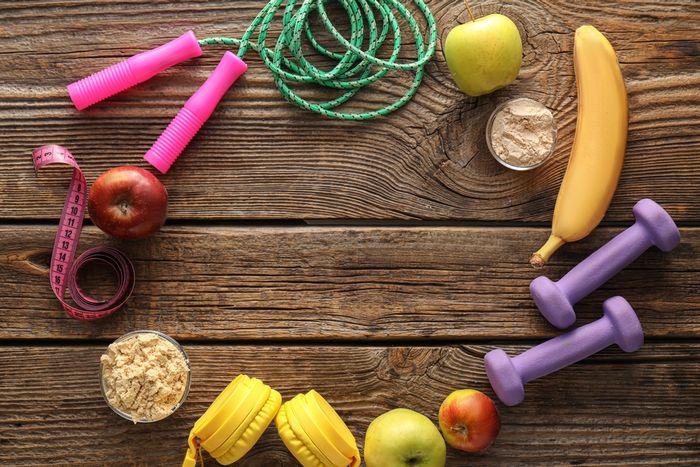 Circular pattern made up of fruit, powdered supplements, and exercise equipment