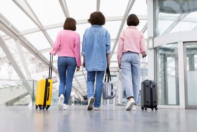 Three ladies carrying their suitcases through a clean airport for a holiday booked through hotels.com