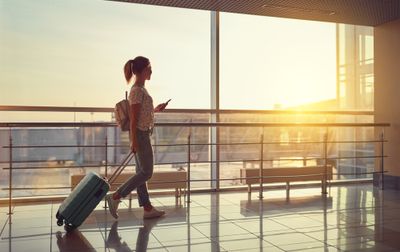A female traveler with luggage using hotel rewards program to go on a trip