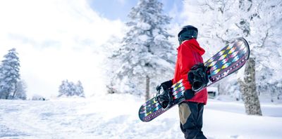 a person in a red jacket carrying a snowboard