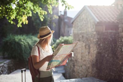 A female solo traveler on a trip in Europe holding a map and looking at the scenery