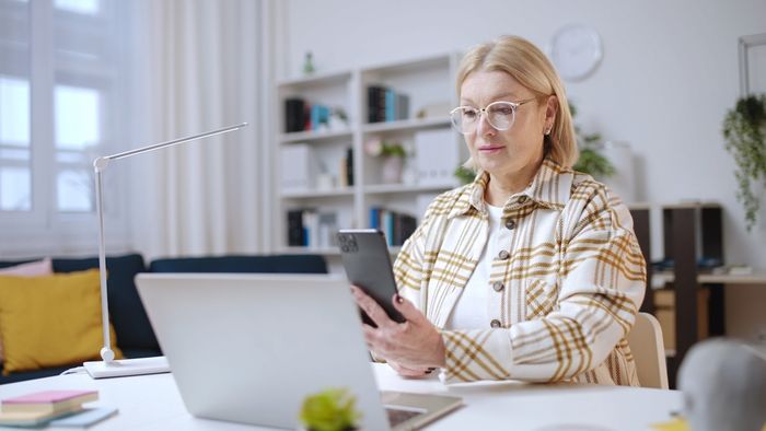 A woman browsing the best global online marketplaces from her laptop and paying effortlessly from her phone