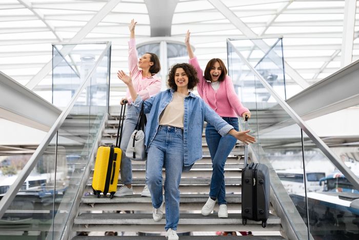 Three women standing on airport staircase celebrating their savings with Booking.com