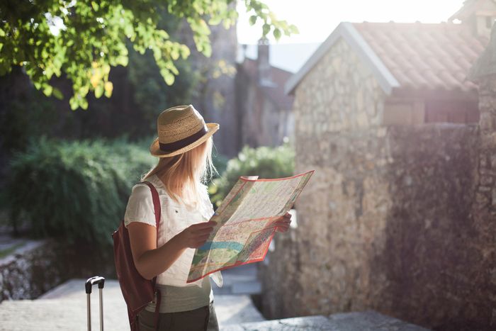 A female solo traveler on a trip in Europe holding a map and looking at the scenery