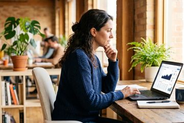 Professional analyzing pricing A/B test data on a laptop in a bright office.