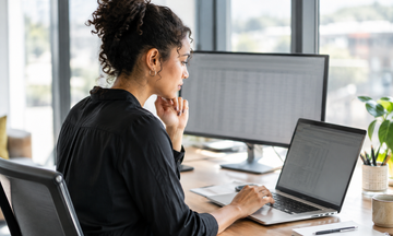A marketing professional reviewing A/B testing alternatives on a laptop in a modern office.