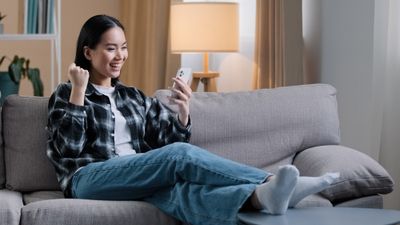 Excited girl sitting on couch looking at her phone in her hand