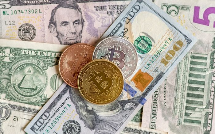 Three Bitcoin on top of different dollar bills