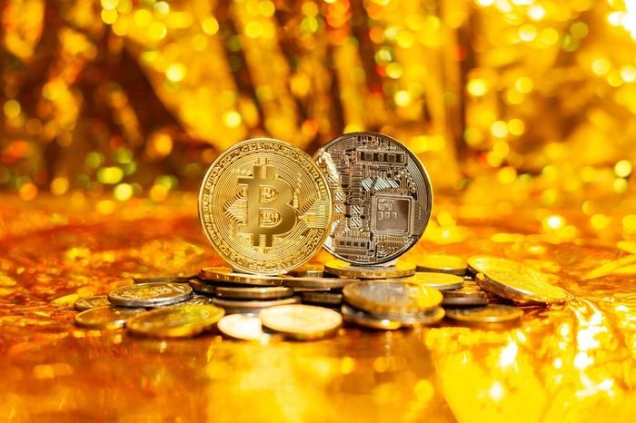 Two Bitcoins on a stack of coins with a gold background
